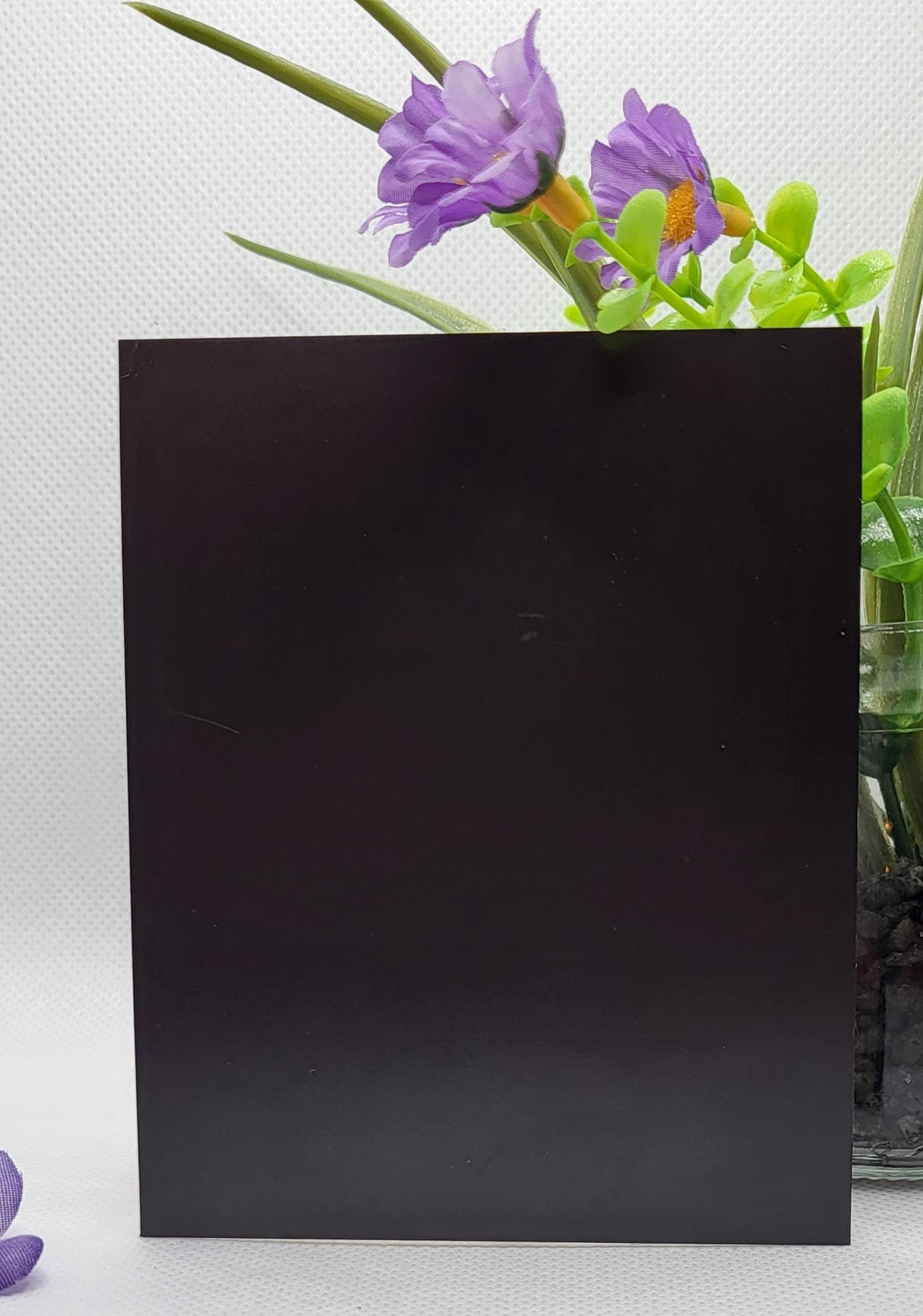 Black square card on a white background with purple flowers