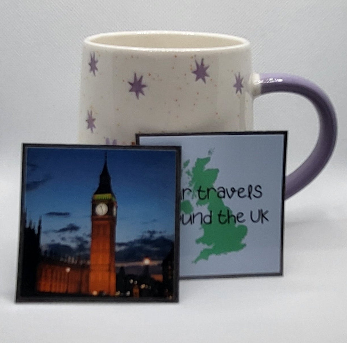 Mug with floral design on a white surface next to a framed picture of a cityscape.